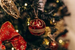 Close-up of a beautifully decorated Christmas tree with a red bauble and warm bokeh lights.